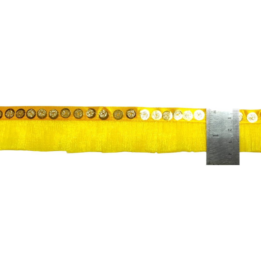 Yellow ribbon with decorative buttons and a ruler for measurement on a white background